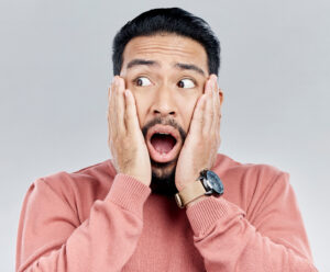 A man holding his hands to his face in a surprised gesture.